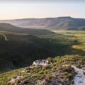 Luxury safari landscape at Bushmans Kloof Wilderness Reserve in South Africa, featuring dramatic sandstone cliffs, vast green plains, and pristine natural scenery in the Cederberg Mountains.