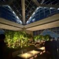 Guests gather beneath the glass atrium during the Park Hyatt Tokyo reopening party, surrounded by candlelit tables and a freshly replanted bamboo garden that symbolizes renewal and quiet luxury above the Shinjuku skyline.